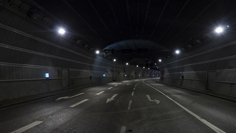 Abgebildet ist ein beleuchteter Straßentunnel.  
