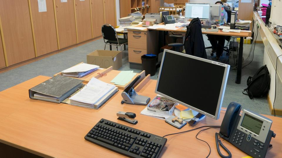 Blick auf einen Schreibtisch der ausgestattet ist mit einem Monitor, Tastatur, Maus und Telefon