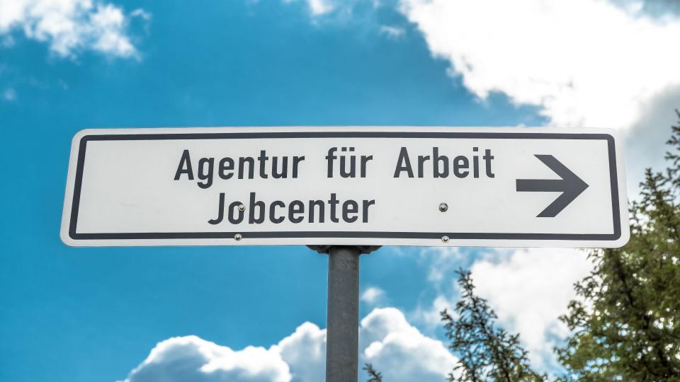Abgebildet ist ein Straßenschild mit der Aufschrift "Agentur für Arbeit - Jobcenter".