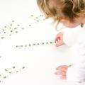 Ein Kleinkind legt aus unsortierten Buchstabenplättchen das Wort "hochbegabt" zusammen.