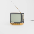 Ein alter, kleiner Schwarz-Weiß-Fernseher mit ausgezogener Antenne vor einem weißen Hintergrund.